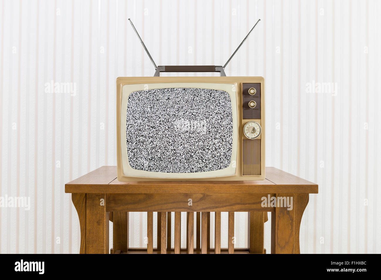 Old television with antenna on wood table with static screen. Stock Photo