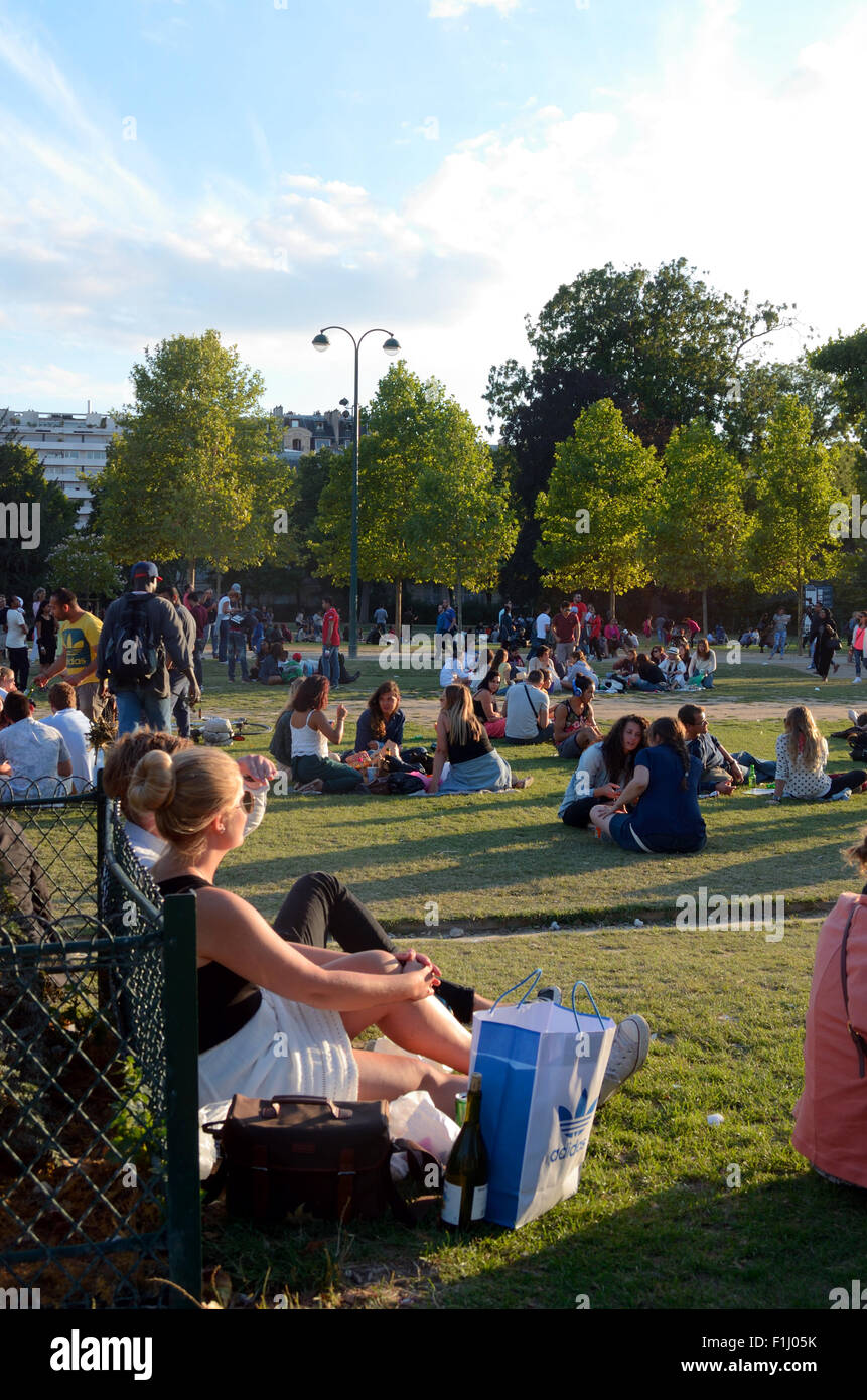 People sat on the ground in parkland behind The Eiffel Tower Stock Photo