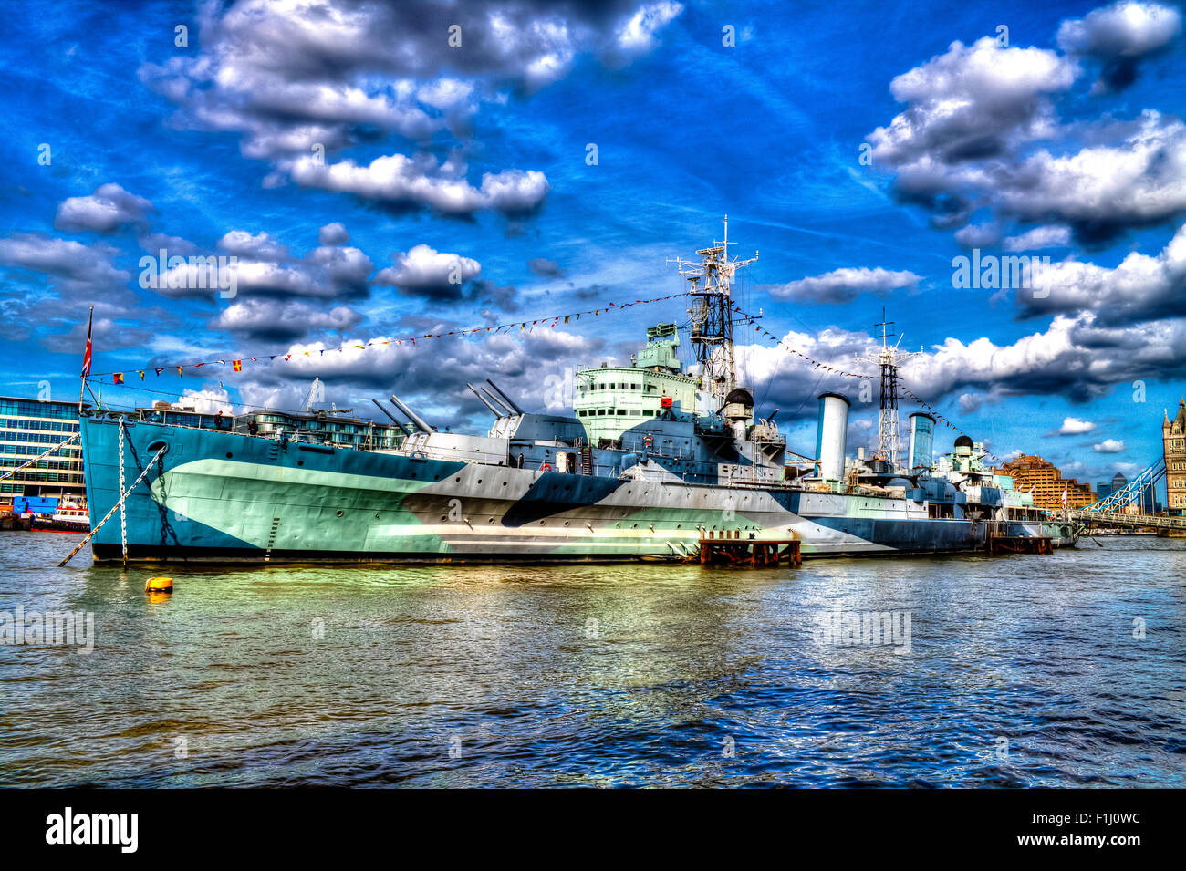 HMS Belfast, famous warship on River Thames. London City on a background. Tourists walking on the deck of the ship. HDR. Stock Photo