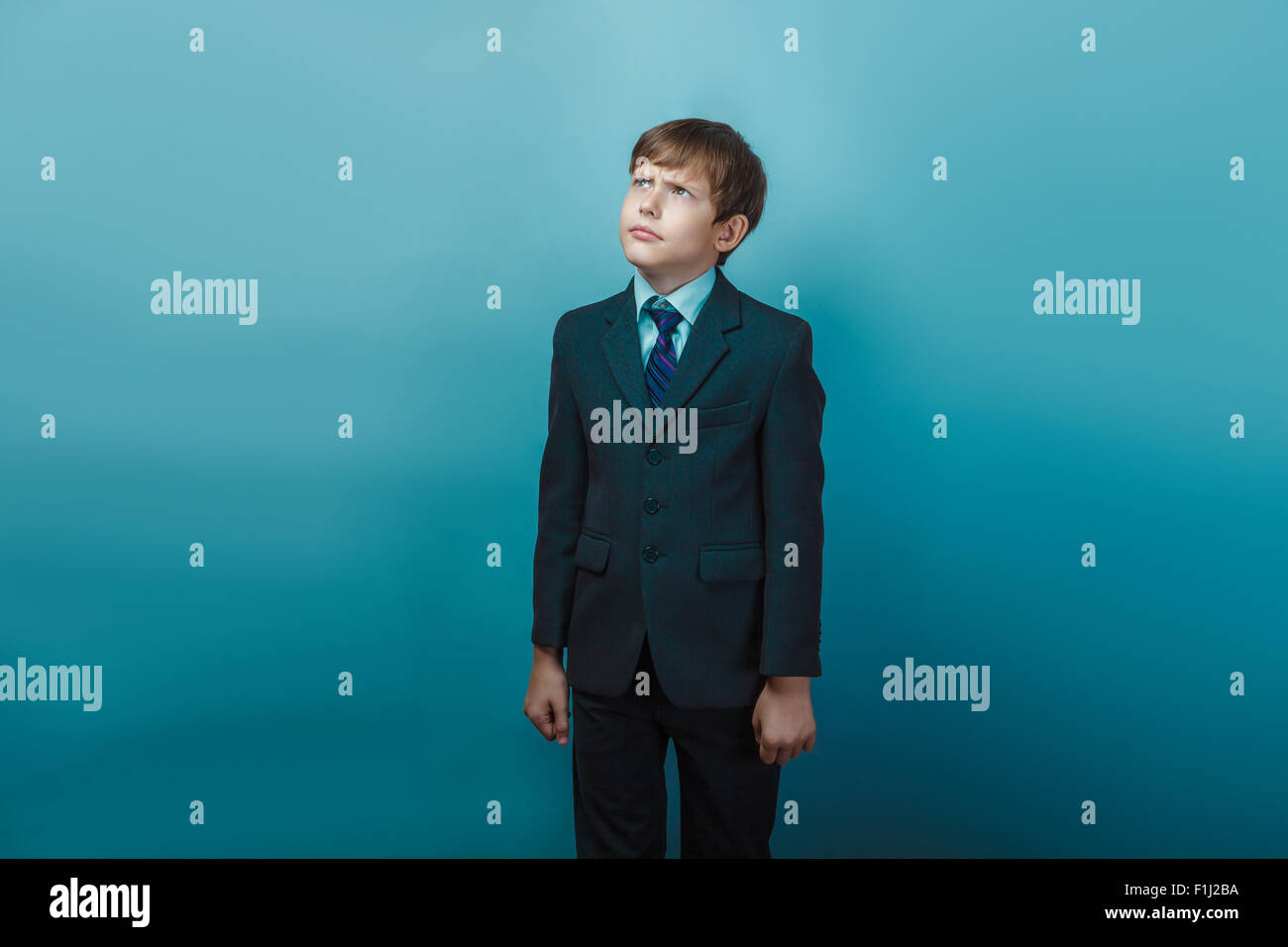 a boy of twelve European appearance in a suit looking up frowns Stock Photo