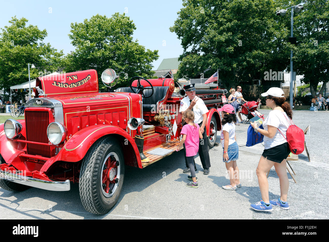 Old fireman showing children an antique fire truck Greenport Long Island New York Stock Photo