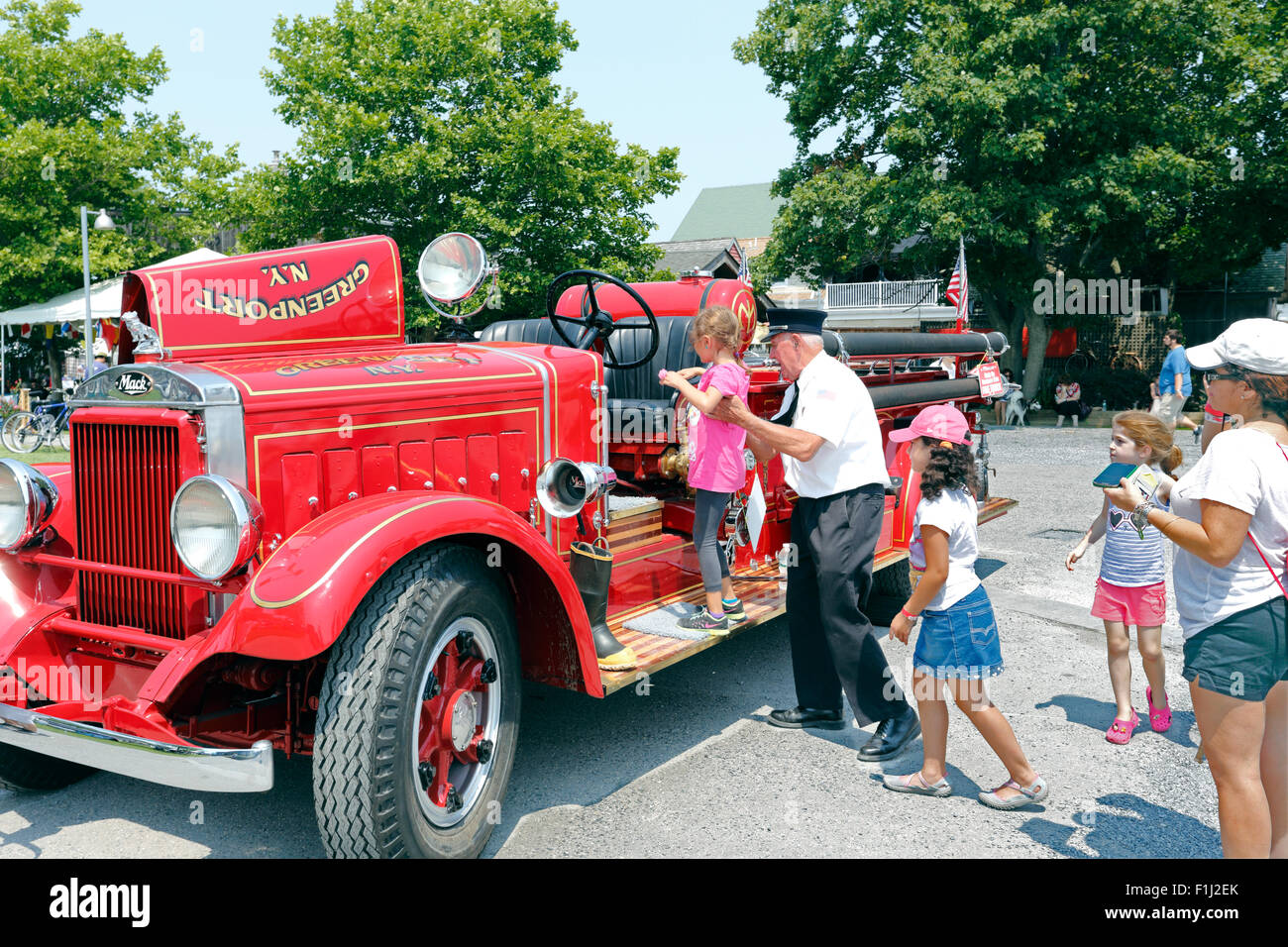 Old fireman showing children an antique fire truck Greenport Long Island New York Stock Photo