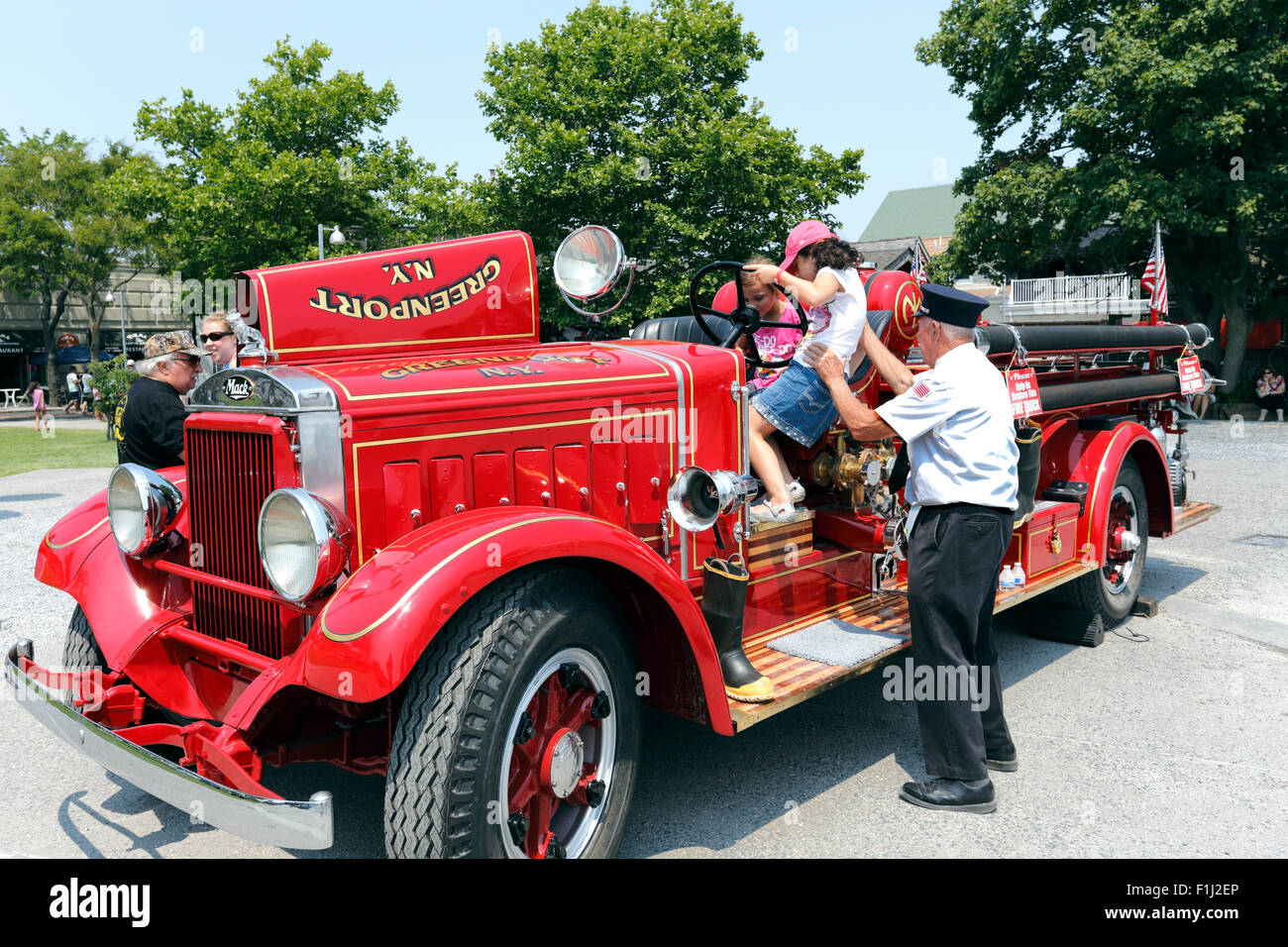 Old fireman showing children an antique fire truck Greenport Long Island New York Stock Photo