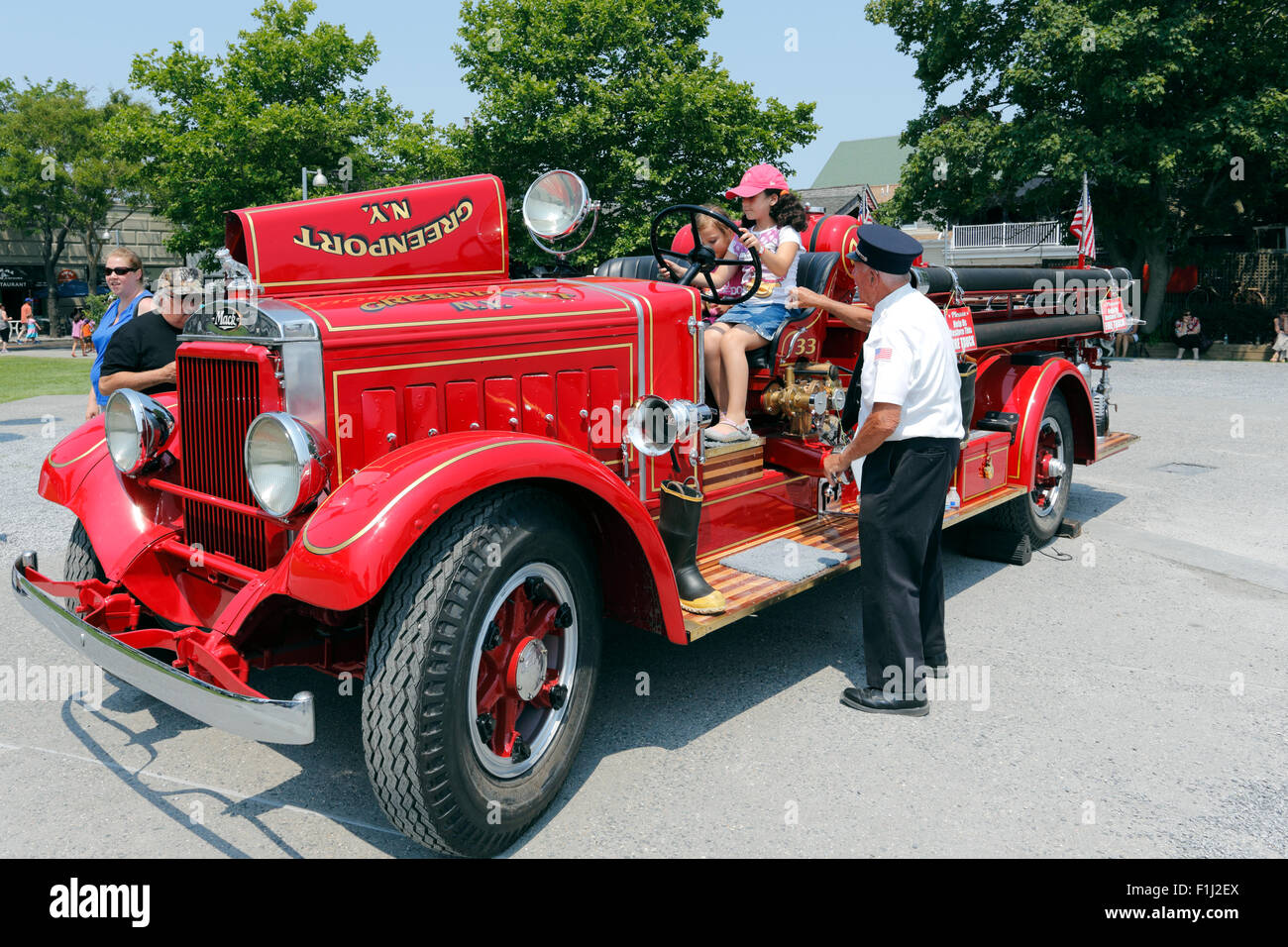 Old fireman showing children an antique fire truck Greenport Long Island New York Stock Photo