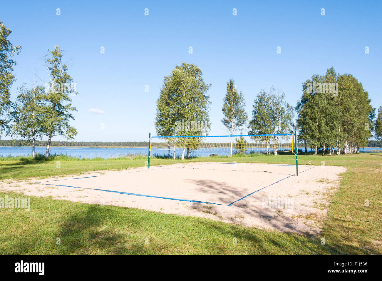 Sandy volleyball field at a lake coast surrounded by grass in a sunny summer day Stock Photo