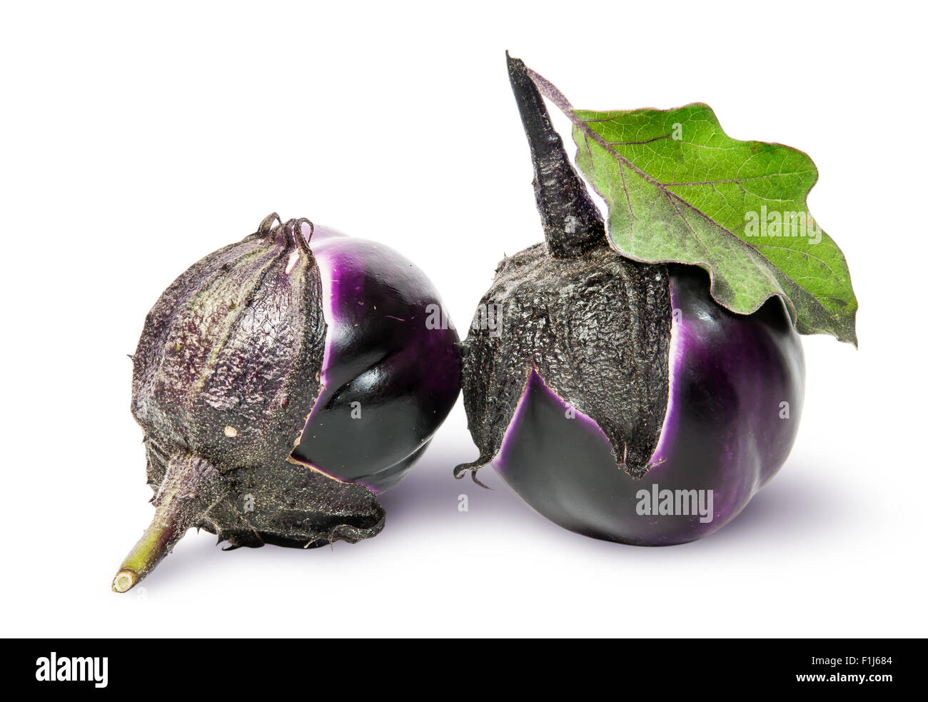 Two round ripe eggplant with green leaf rotated isolated on white background Stock Photo