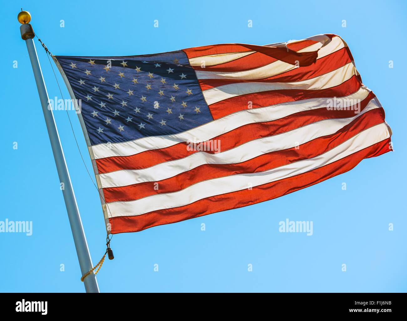 American Flag on a Pole. Waving United States Flag on the Blue Sky. Stock Photo