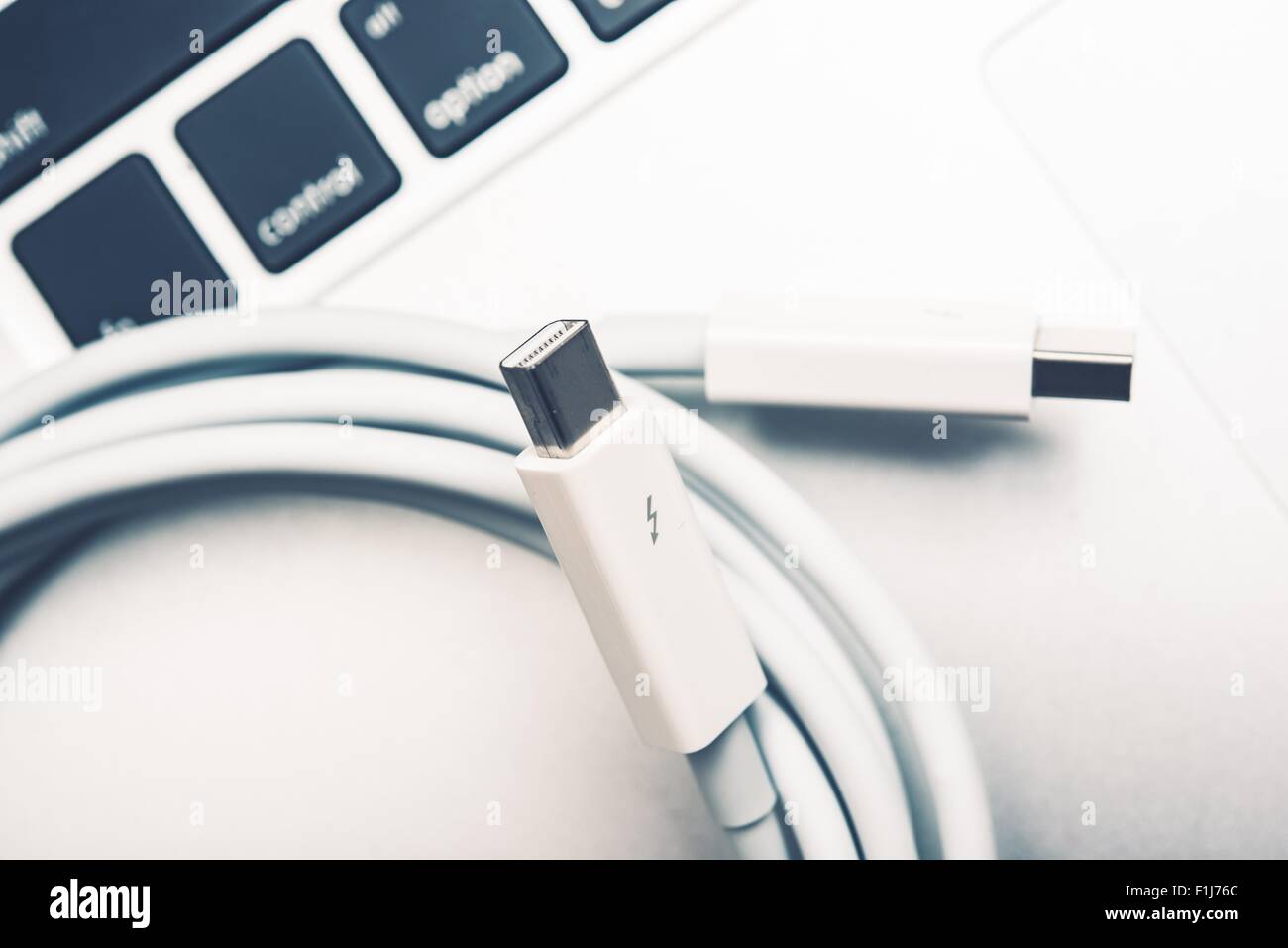 White Thunderbolt Cable and the Laptop Keyboard Stock Photo