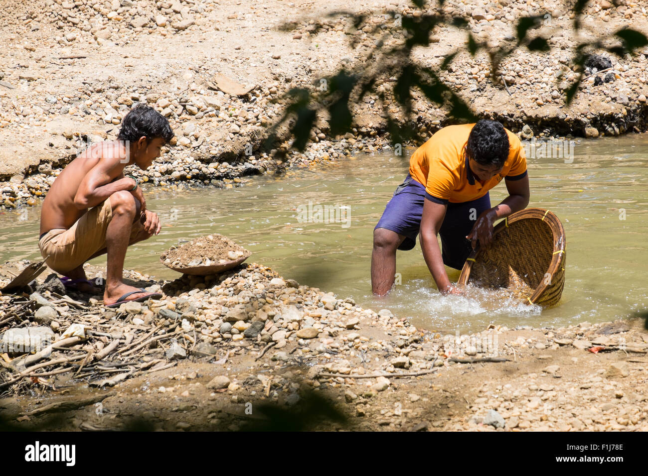 Two illegal gem prospectors pan for gemstones in the gravel deposits of a river in Uva province, Sri Lanka. Stock Photo