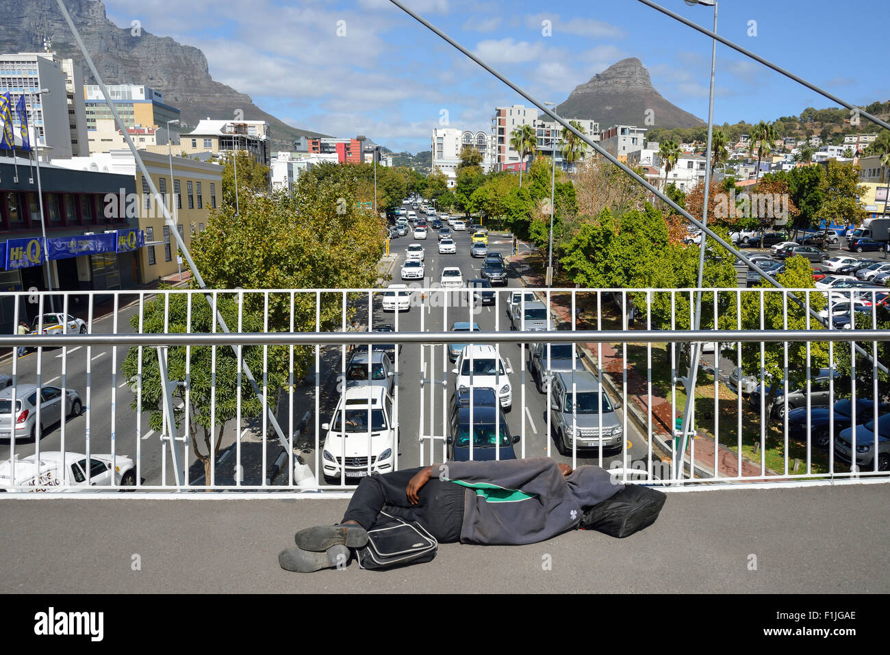 Homeless black man lying on pedestrian overpass, Buitengragt Street, Cape Town, Western Cape Province, Republic of South Africa Stock Photo