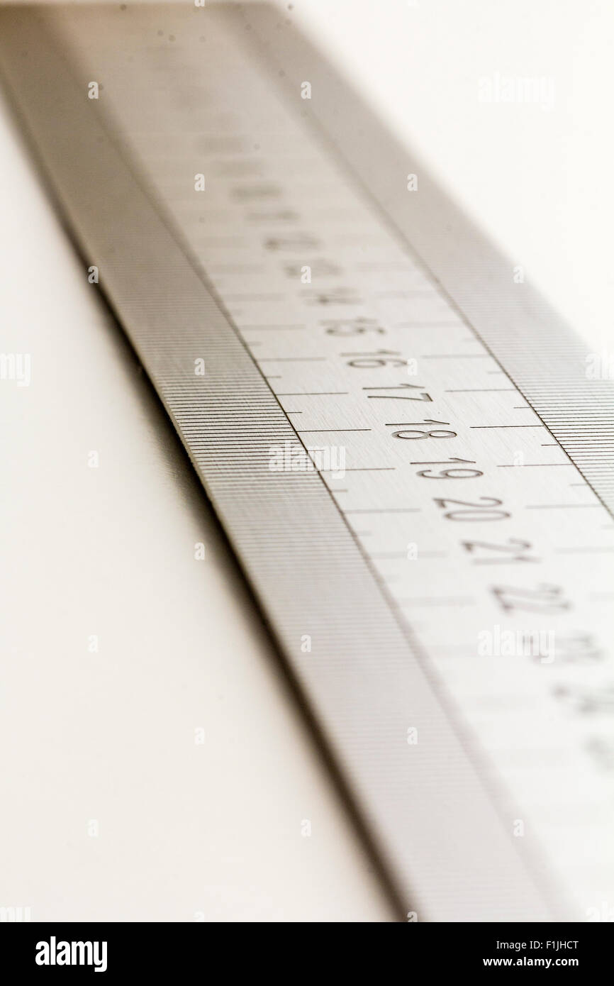 Grey metal ruler on plain white background, selective focus, viewed ...