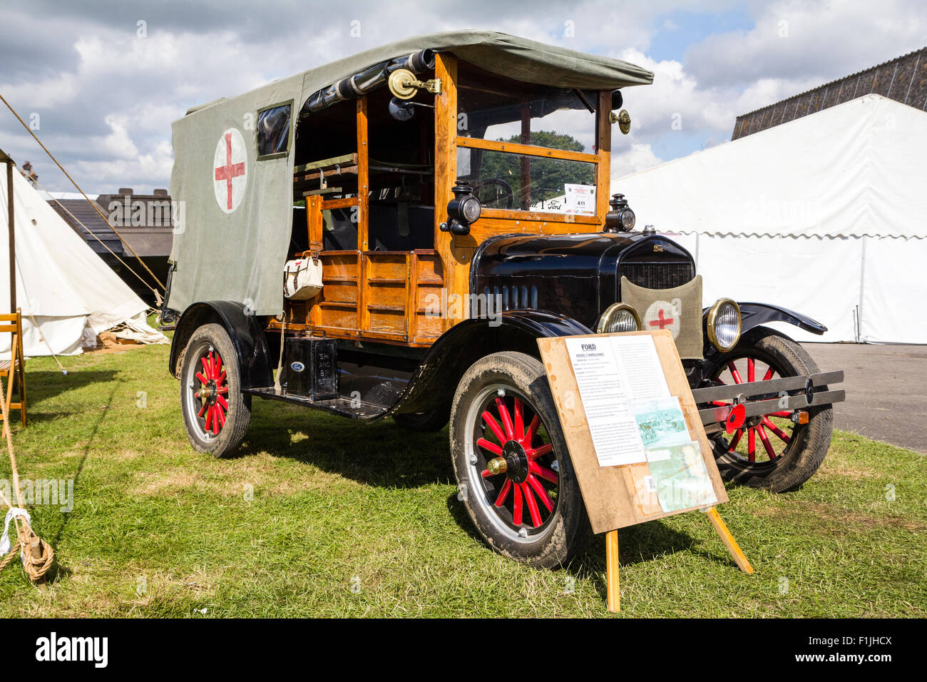 World War One vintage ambulance, a Ford model T, parked on grass with tents around with display board in front. Stock Photo