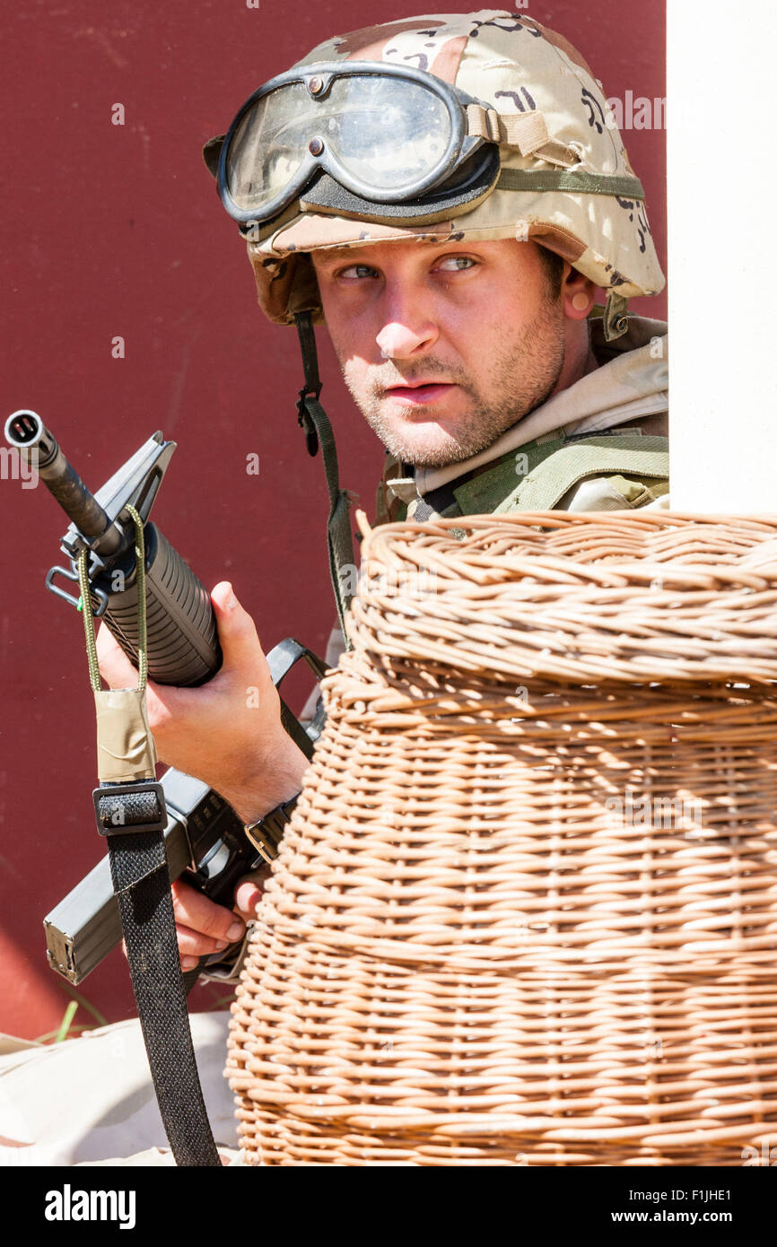 American army, black Hawk reenactment at War and Peace show. Soldier taking cover behind basket, while holding M16 at the ready. Set in Mogadishu. Stock Photo