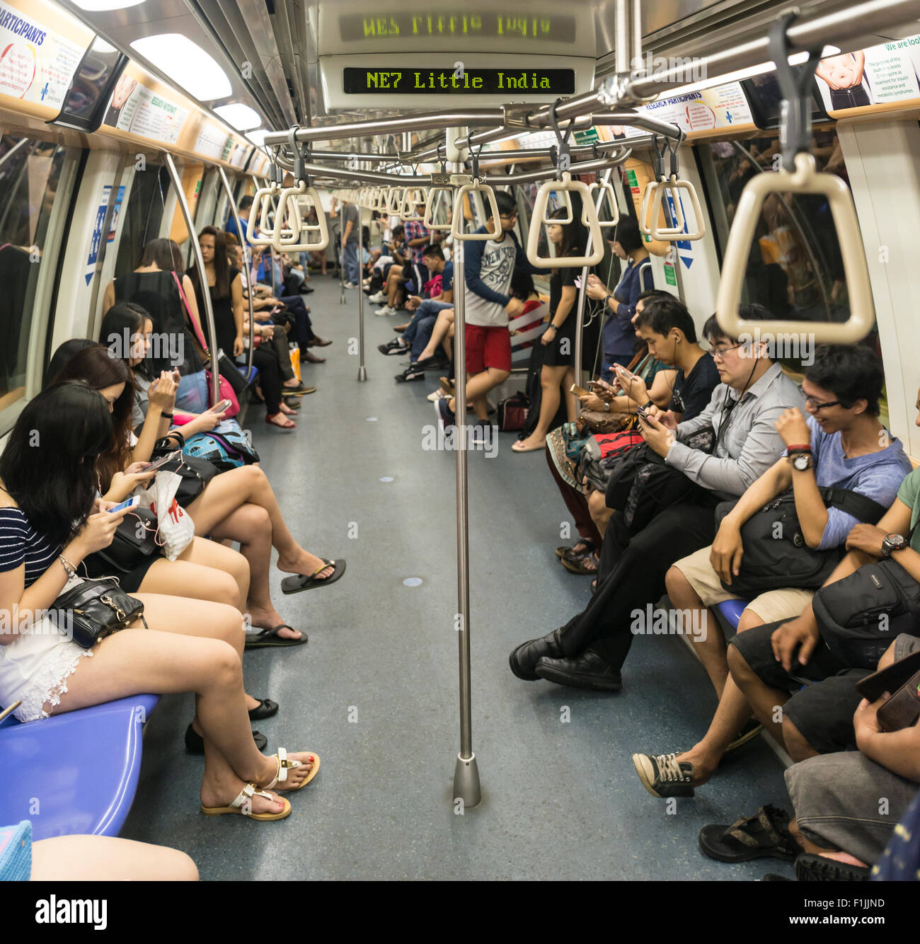 Asian people sitting in a subway train, Little India station, Singapore Stock Photo