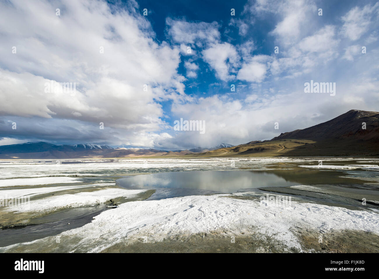 Layers of salt, barren landscape, blue sky and dark clouds at Tso Kar, a fluctuating salt lake, 4,530 m, Changtang area, Thukje Stock Photo