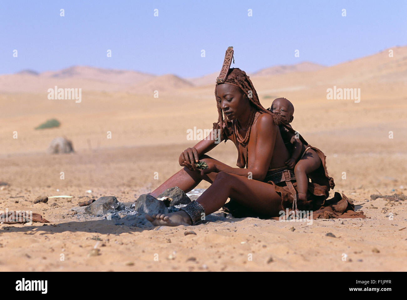Himba Woman and Child Sitting Near Fire, Namibia, Africa Stock Photo