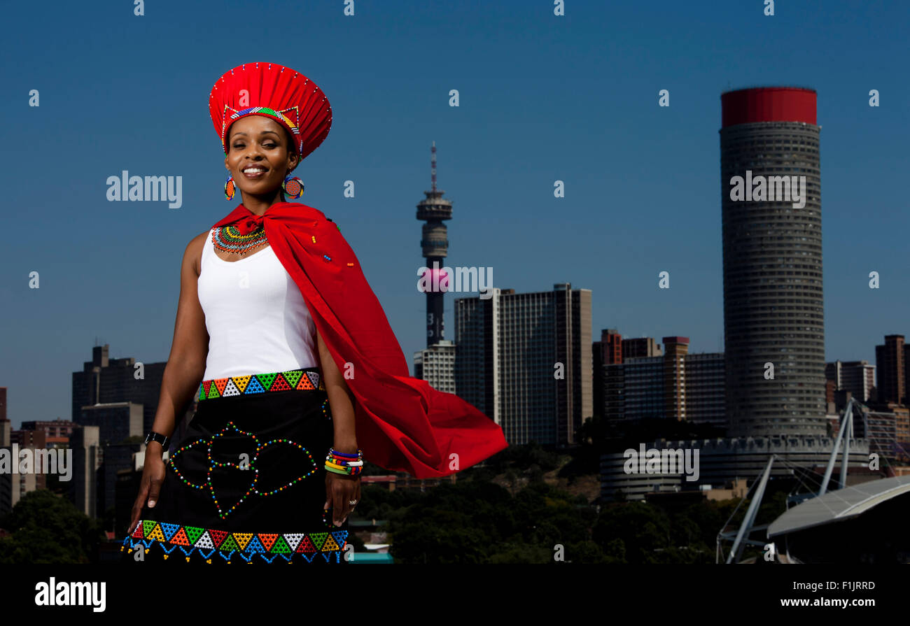 Traditionally dressed African woman stands with cityscape in background Stock Photo