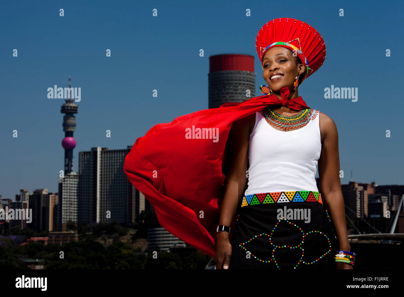 Traditionally dressed African woman stands with cityscape in background Stock Photo