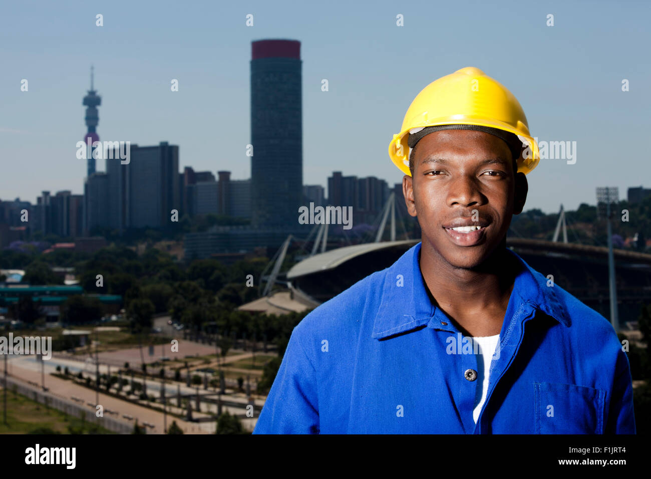 Man with hardhat stands with cityscape in background Stock Photo