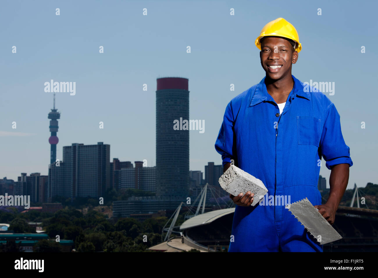 Construction worker laying bricks with cityscape in background Stock Photo