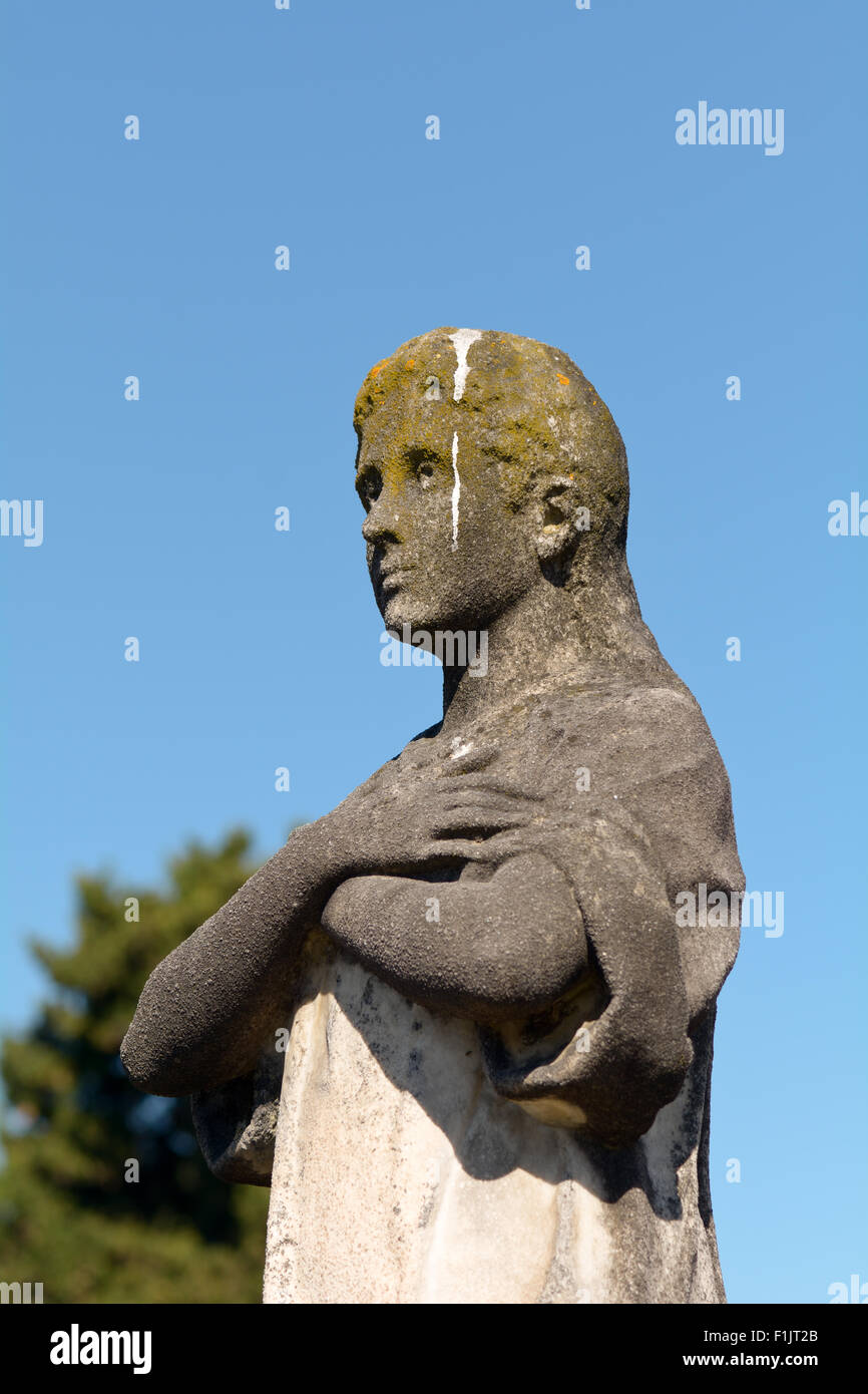Grave stone statue of man covered in bird poo and yellow lichen in
