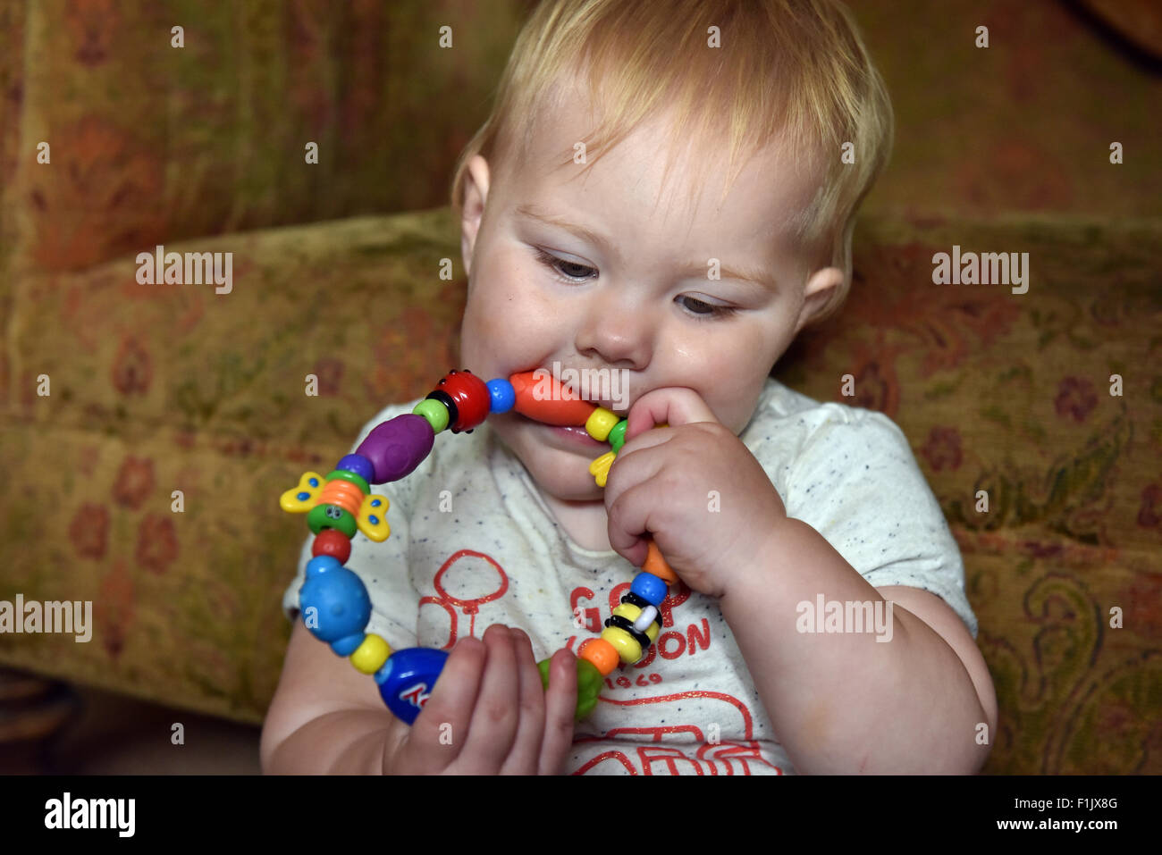 A teething eleven month old baby biting on a teething ring to alleviate