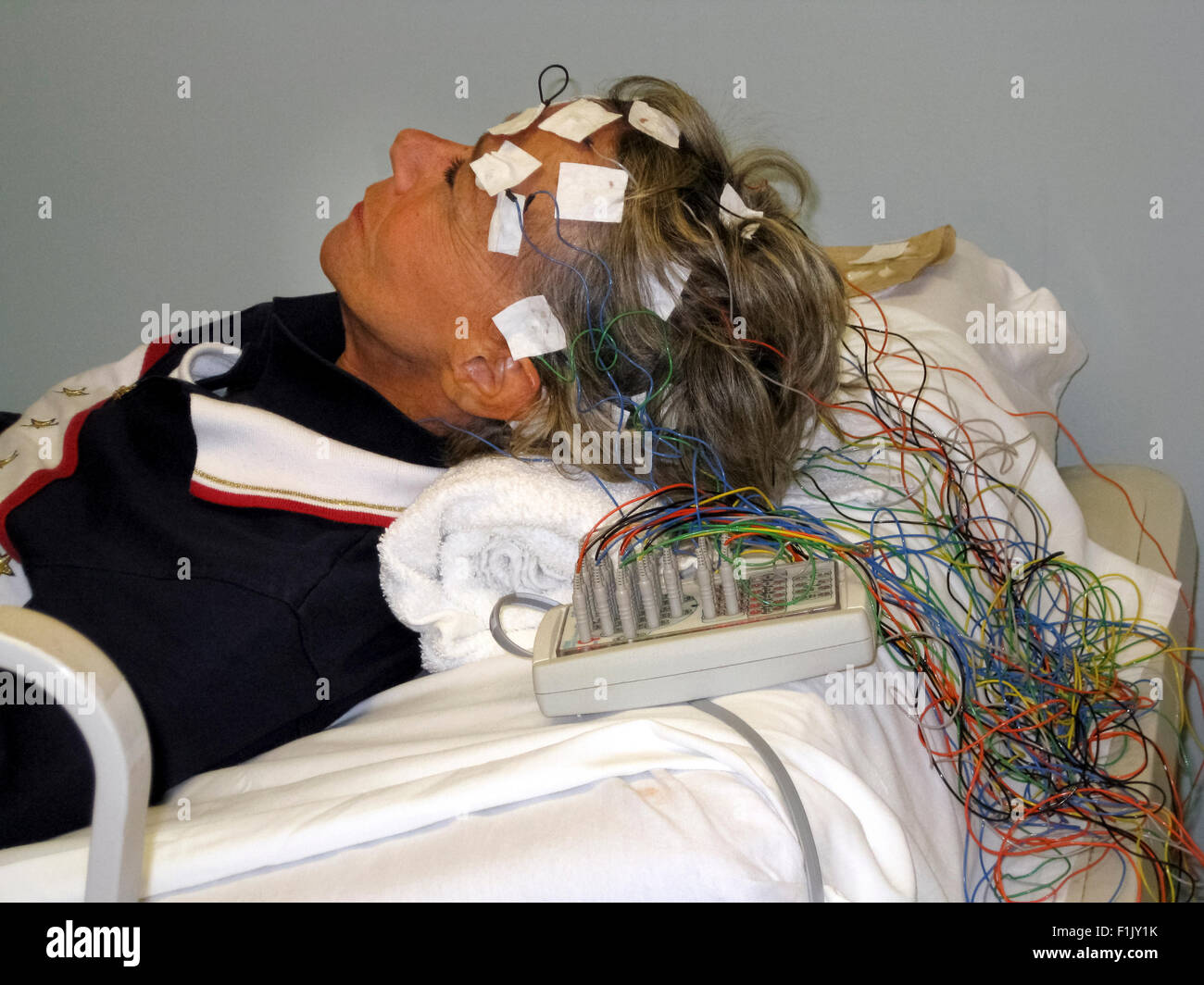 A woman in a doctor's office undergoes electroencephalogram (EEG) testing to detect abnormalities in the electrical activity of her brain. Stock Photo