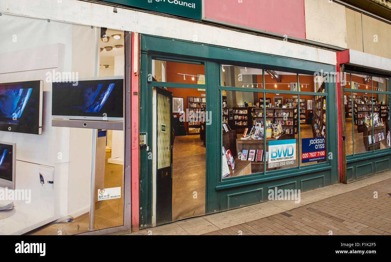 Empty shop with posters in the windows to make it look less derelict on a high street in West Bromwich, West Midlands, England. Stock Photo