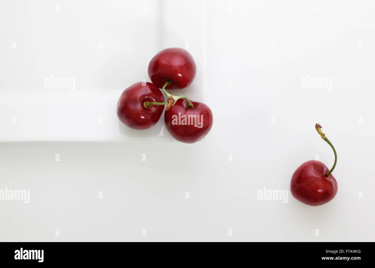 Red cherries on white plate overhead Stock Photo
