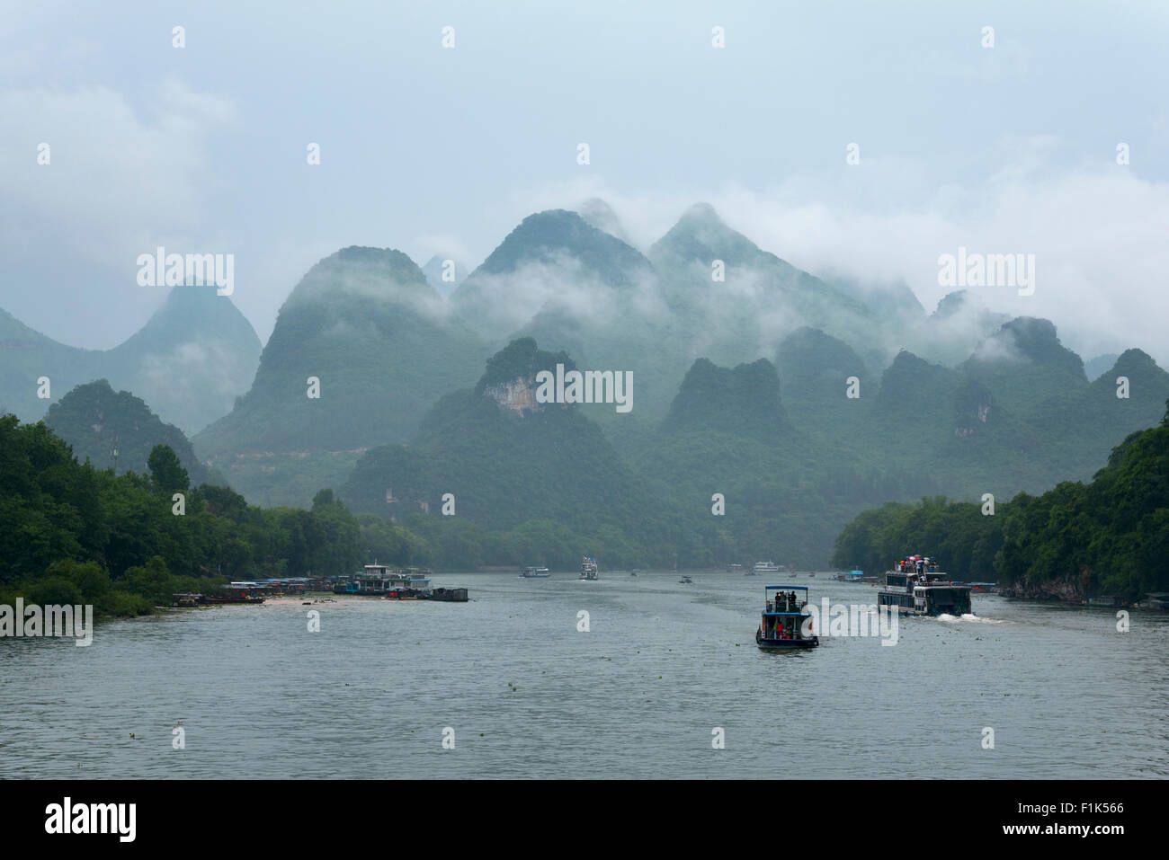 small boats and the cruise ships on Li river in China against transcendental mountains and tropical vegetation Stock Photo