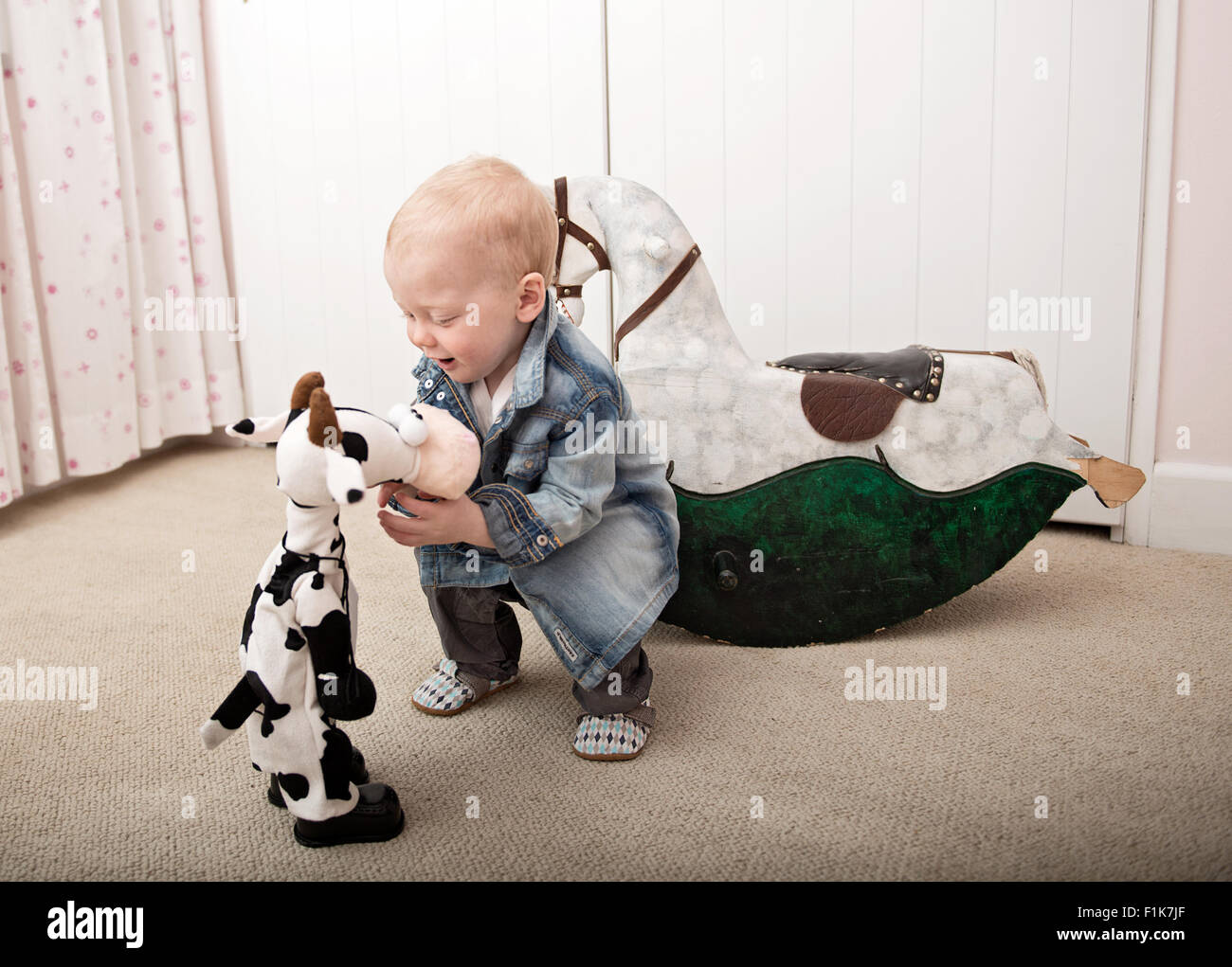 Smiling infant playing with teddies on playroom floor Stock Photo