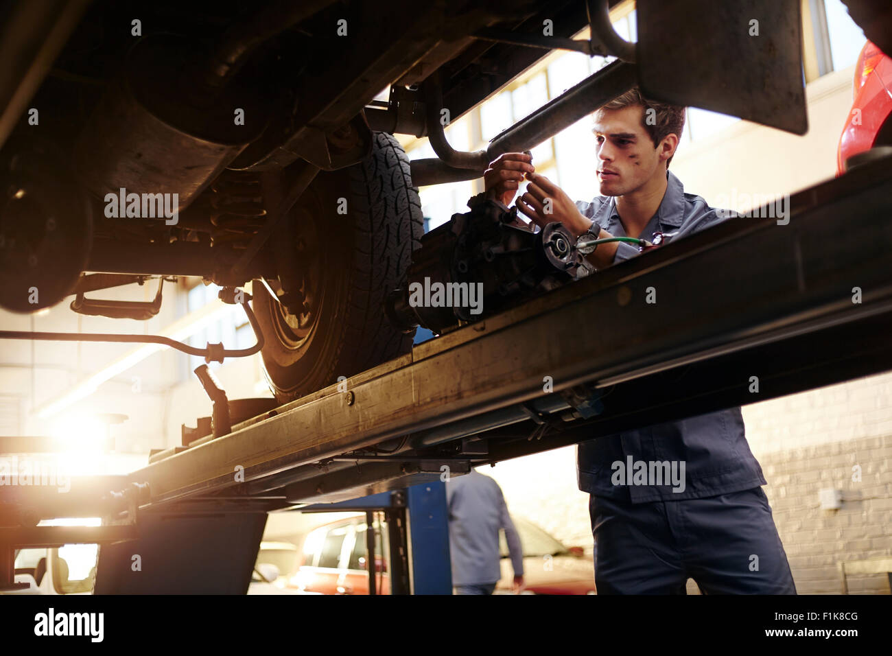 Mechanic working under car in auto repair shop Stock Photo - Alamy
