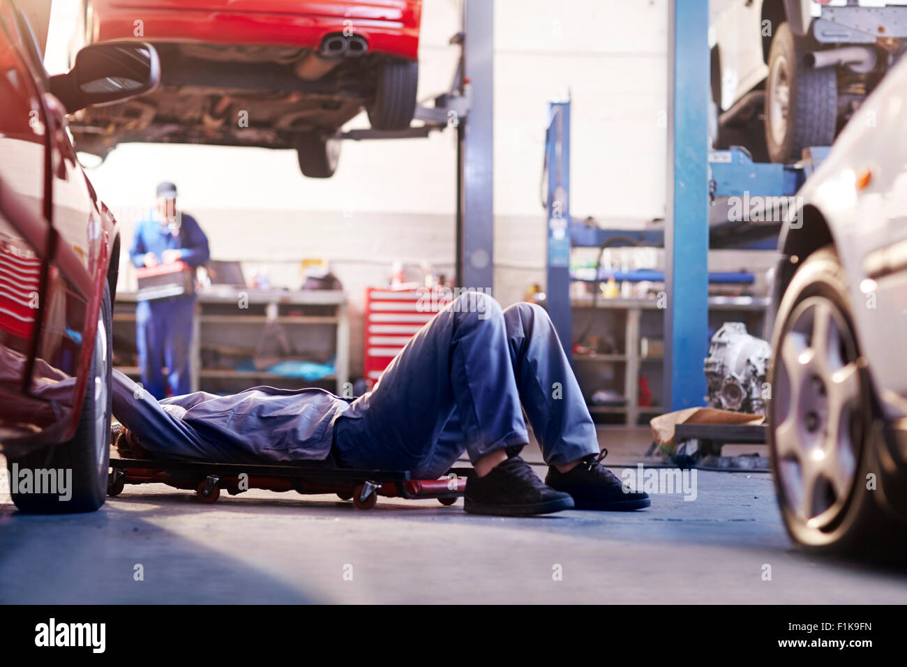 Mechanic under car in auto repair shop Stock Photo