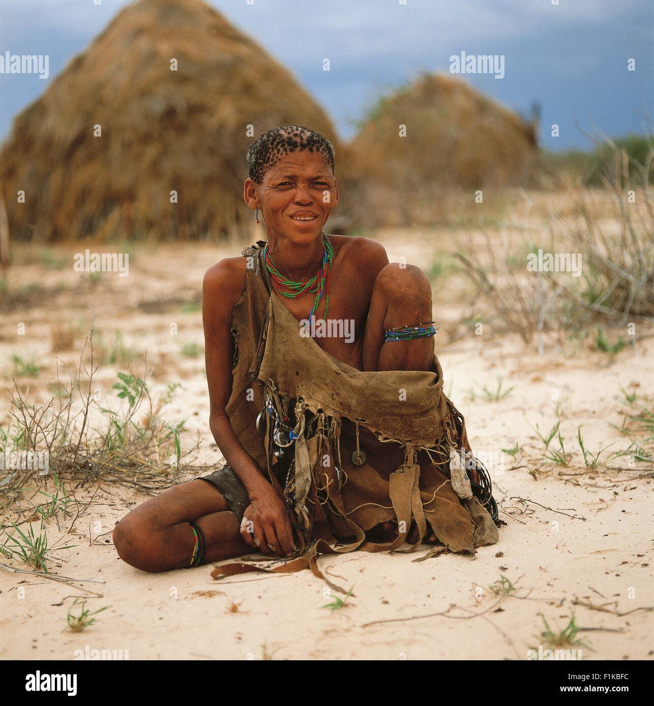 Portrait of Bushman woman sitting in front of village. Botswana, Africa Stock Photo
