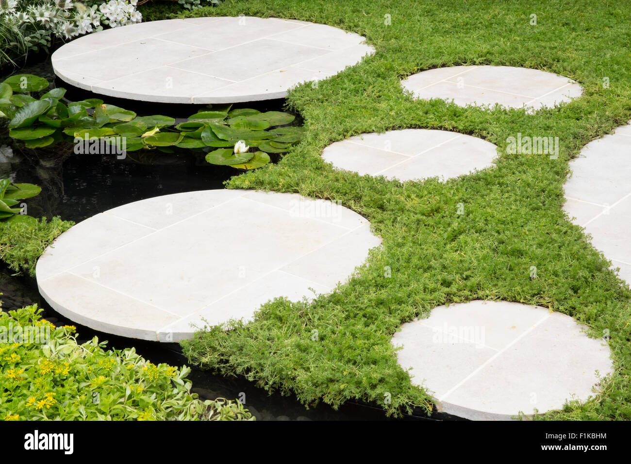 small garden with chamomile lawn and round paving stone stepping stones water feature pond Living Landscapes RHS Hampton Court Flower Show UK Stock Photo