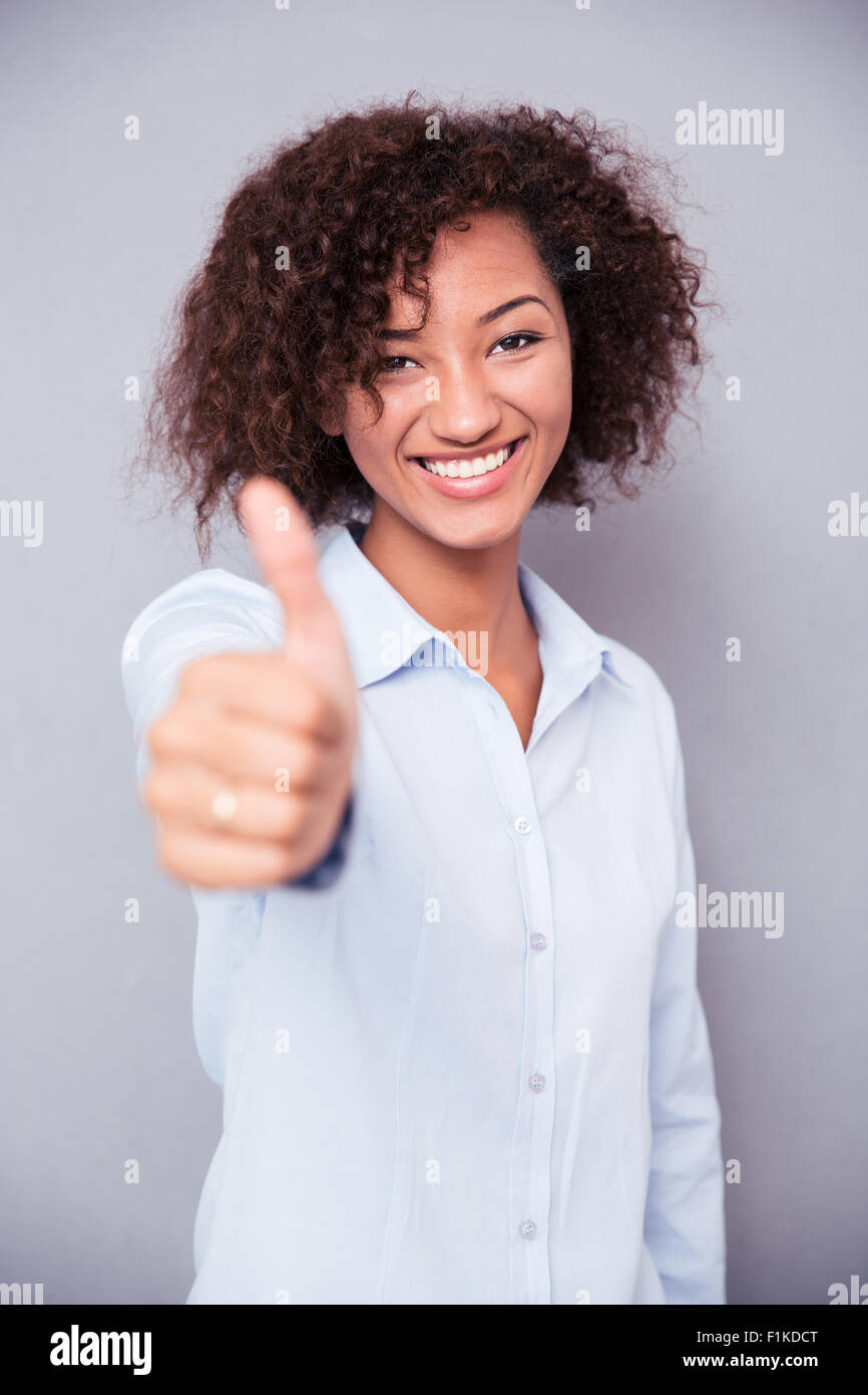 Portrait of a smiling afro american woman with curly hair showing thumb ...