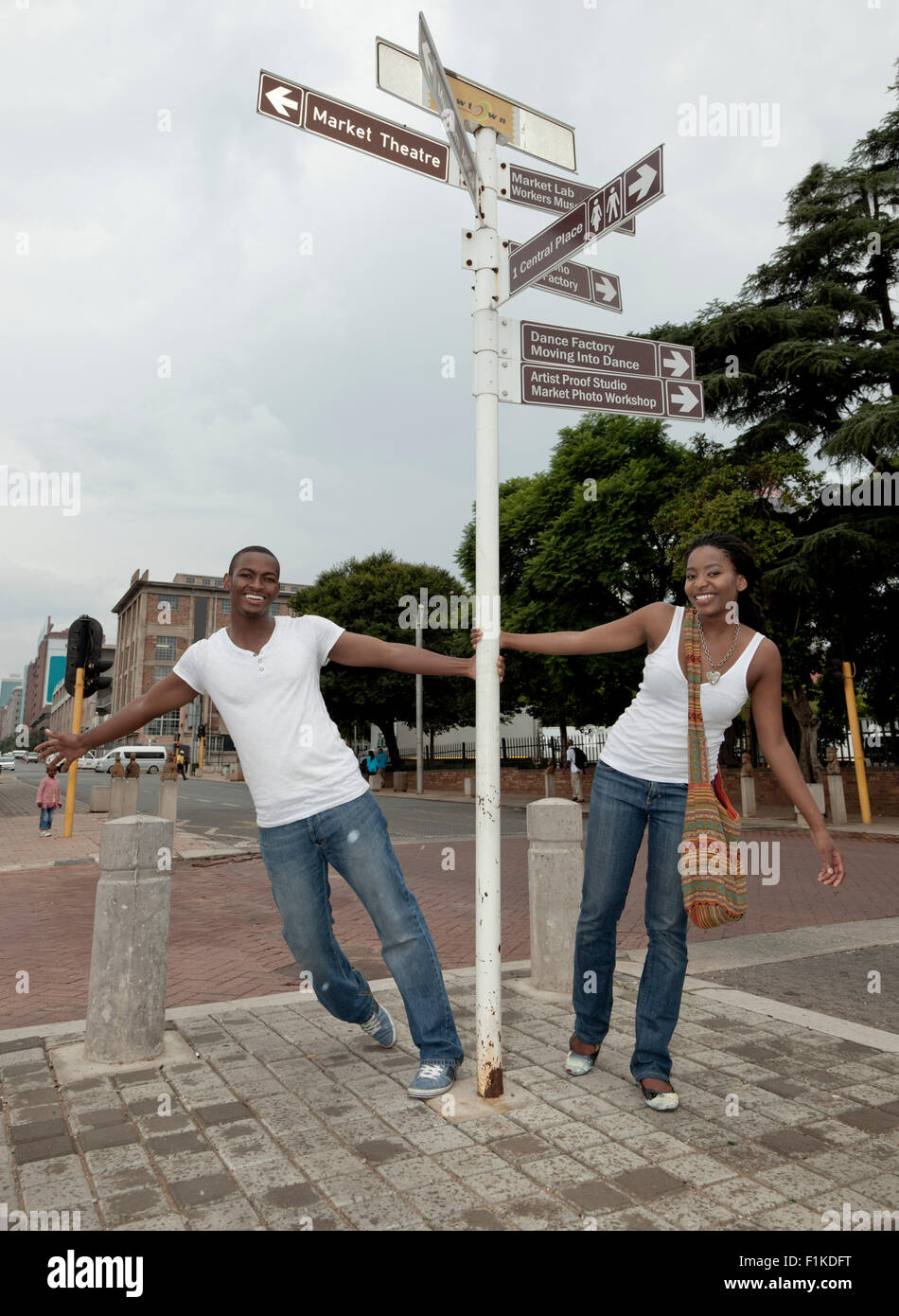 Young African couple swinging on a signpost on the streets of