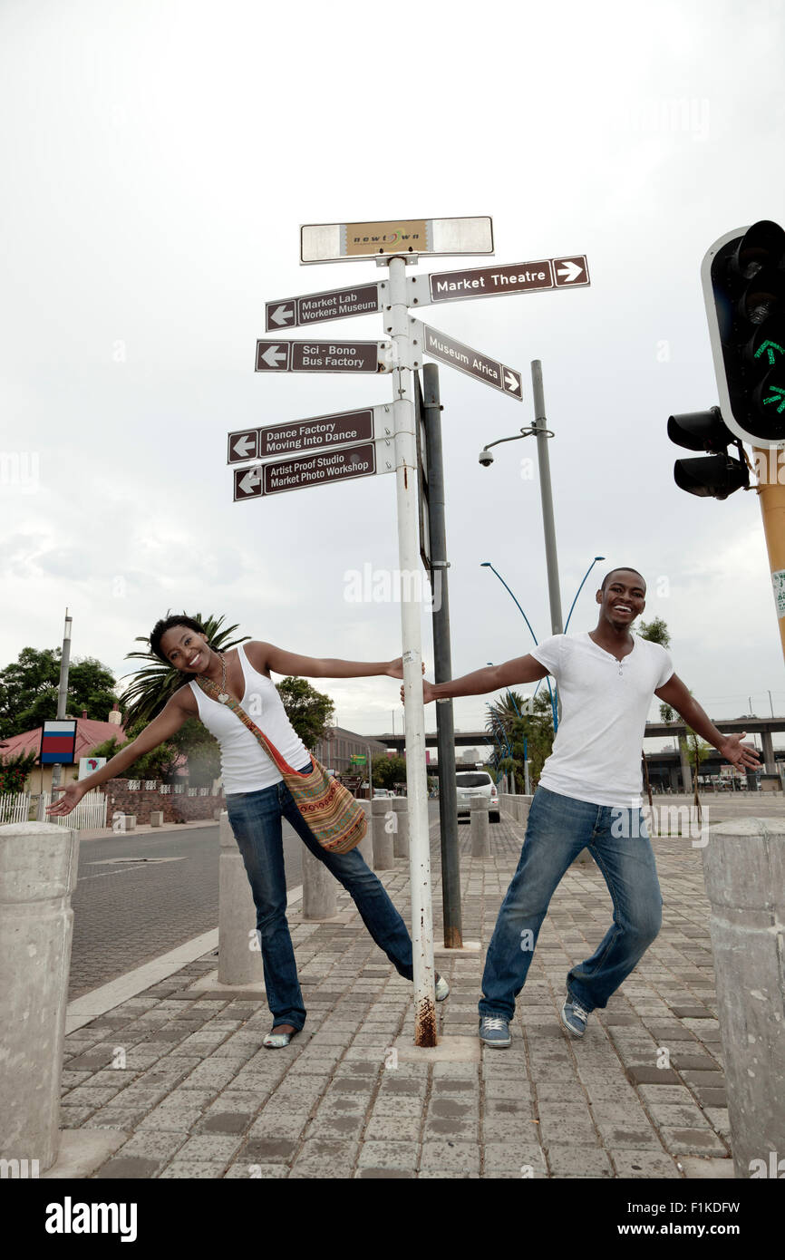 Young African couple swinging on a signpost on the streets of
