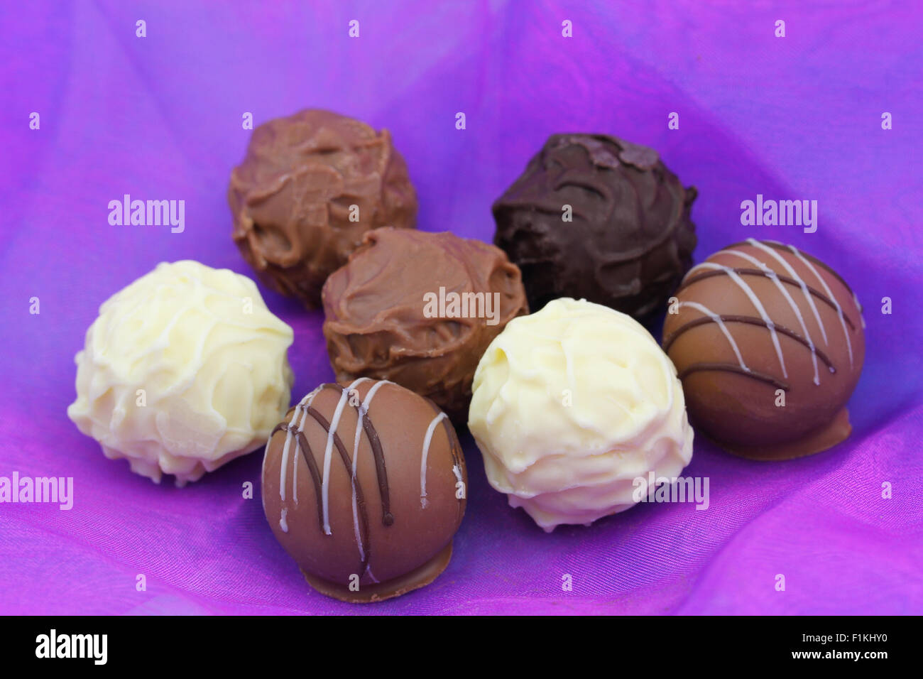 Assorted chocolates, pralines and truffles on purple background Stock ...