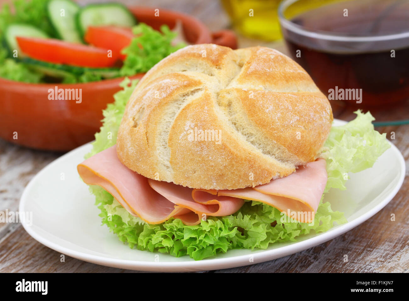 Ham roll with lettuce and bowl of green salad Stock Photo