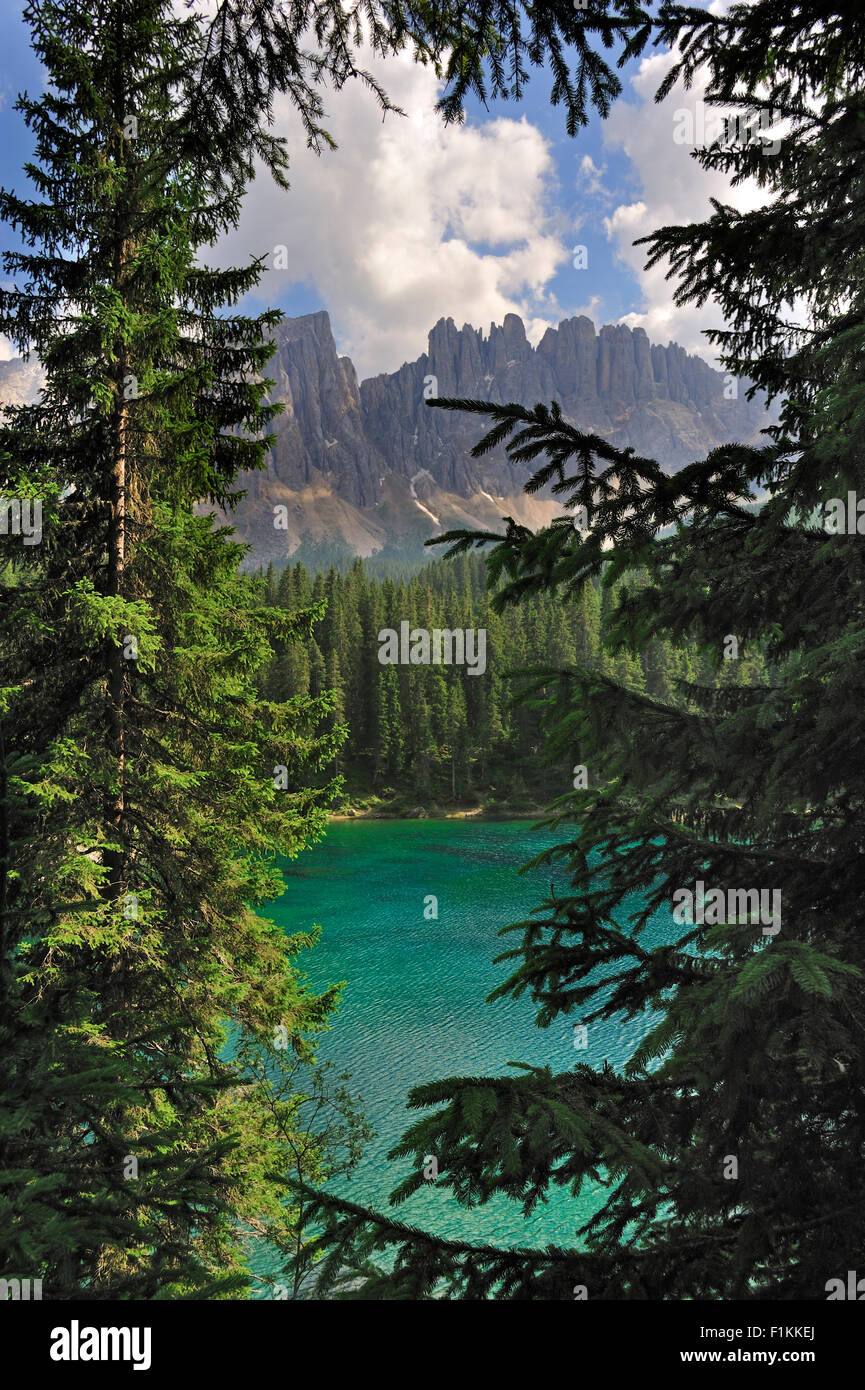 Turquoise water of lake Lago di Carezza / Karersee surrounded by pine forest and mountains, Dolomites, South Tyrol, Italy Stock Photo