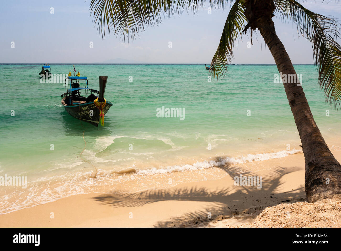 Late morning on a beach where a water taxi waits, Koh Phi Phi Don, Thailand. Stock Photo