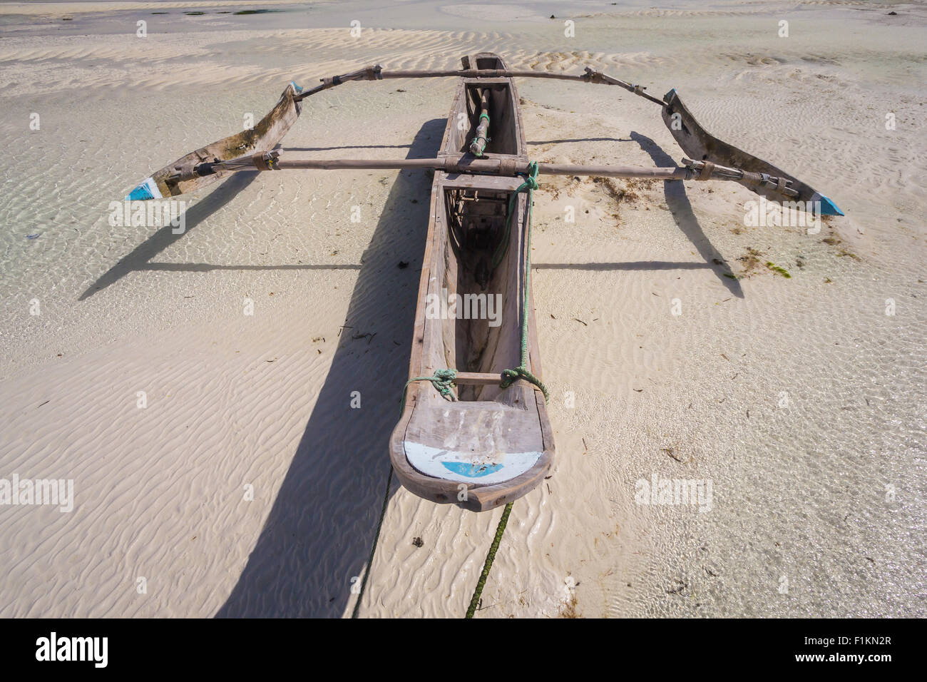 Dhow wooden boat lying dry at low tide on a beach at the Indian Ocean near Zanzibar, Tanzania Stock Photo