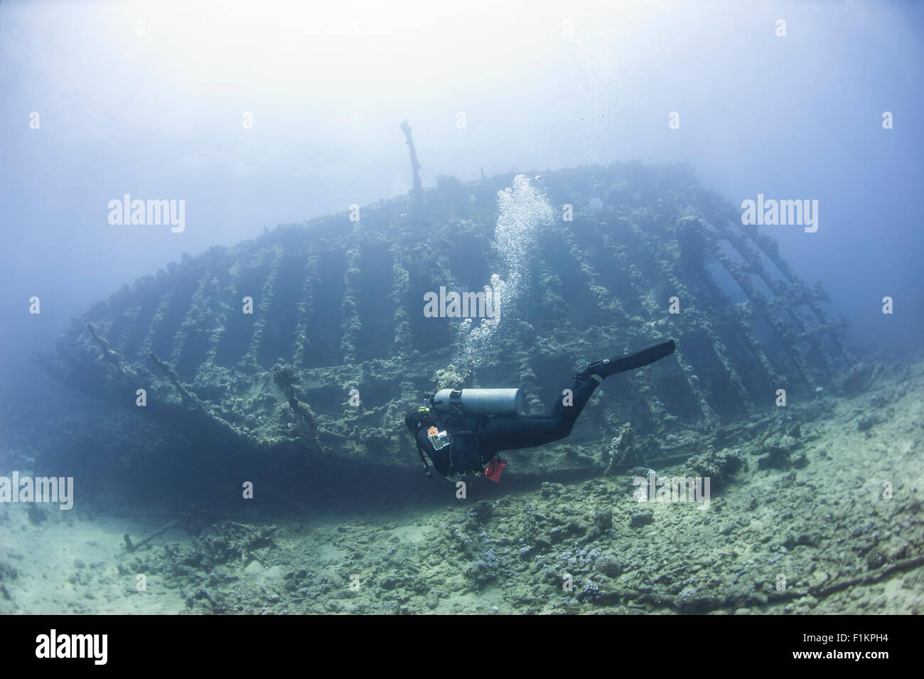 Scuba divers exploring the bow section of a large underwater shipwreck Stock Photo