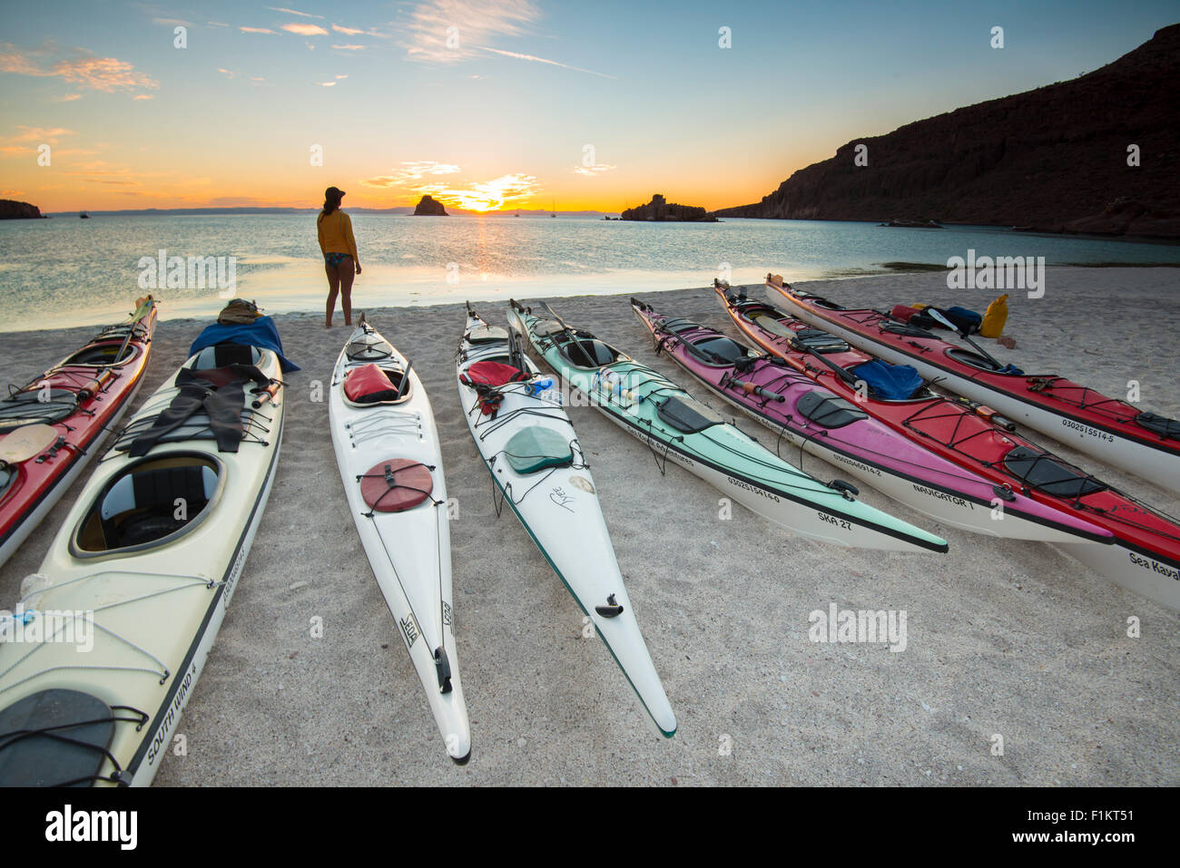Mexico, Baja, Lapaz, Espiritu Santo. Woman standing near kayaks during sunset. Stock Photo