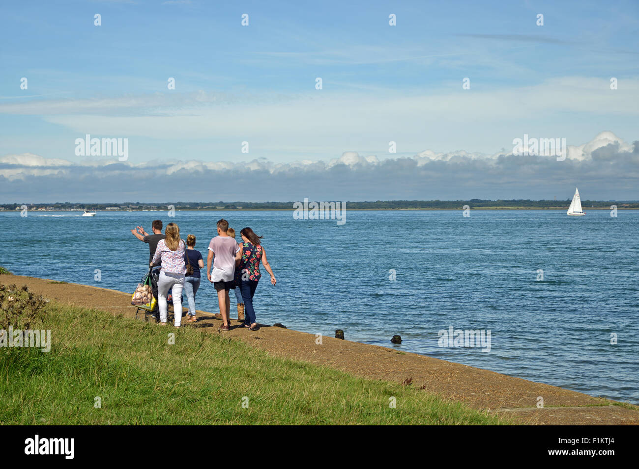 Young adults walking on pathway of sea front in the Isle of Wight United Kingdom Stock Photo