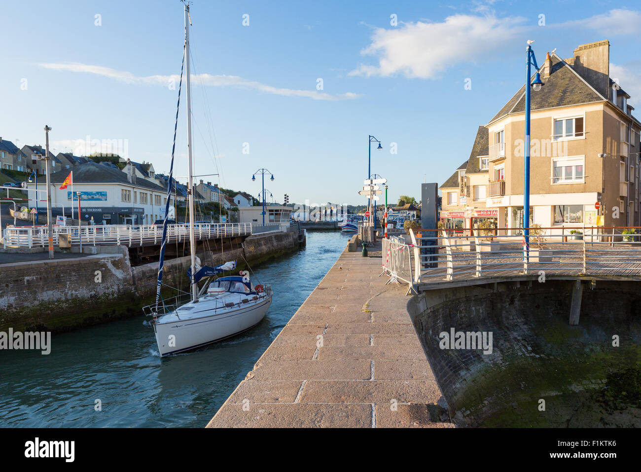A sailing yacht heads through the lock at Port-en-Bessin Huppain, Calvados, Normandy, France and heads out to sea Stock Photo