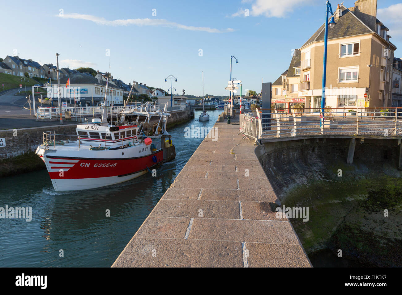 A fishing trawler heads through the lock at Port-en-Bessin Huppain, Calvados, Normandy, France and heads out to sea Stock Photo