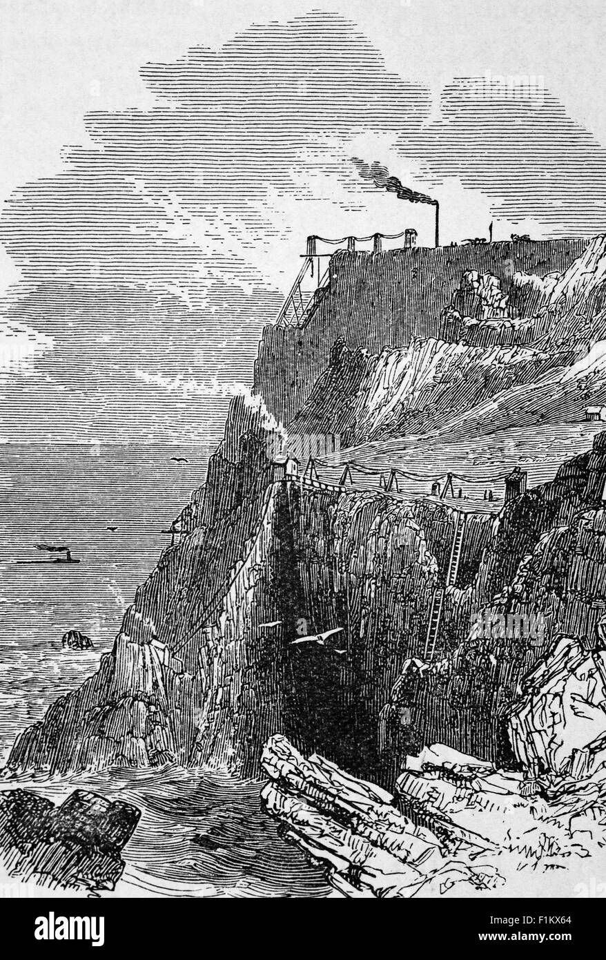A 19th Century view of Cornish clifftop tin mine buildings. At its height the Cornish tin mining industry had around 600 steam engines working to pump out the mines (many mines reached under the sea and some went down to great depths). Stock Photo