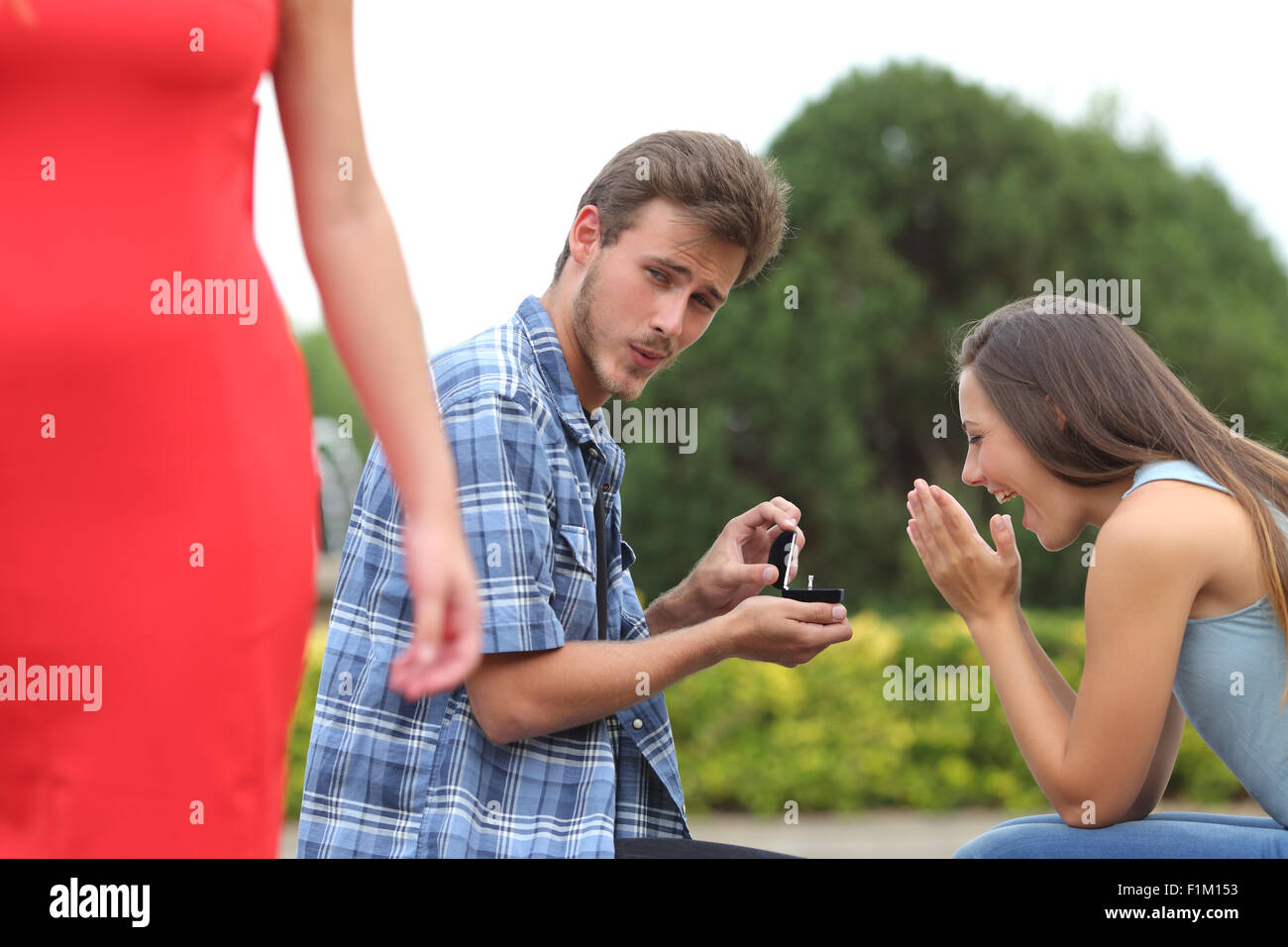 Cheater man cheating during a marriage proposal with his innocent girlfriend Stock Photo